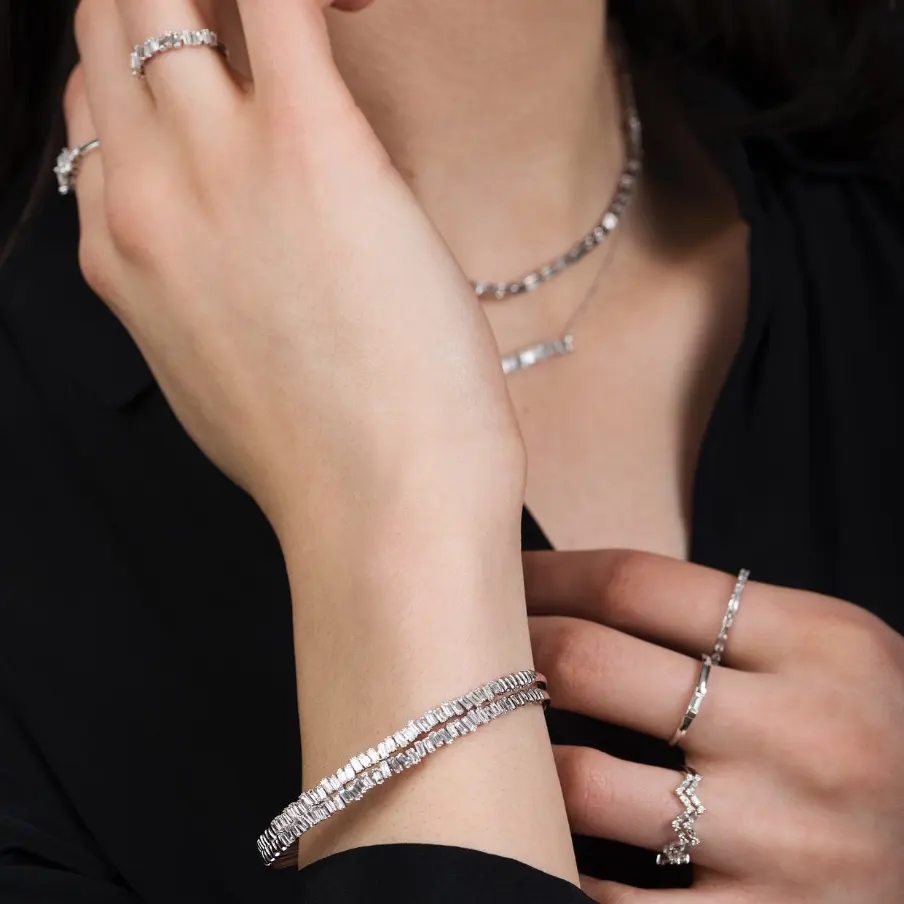 Close up of woman's hands showing a silver bracelet, rigns, and necklaces