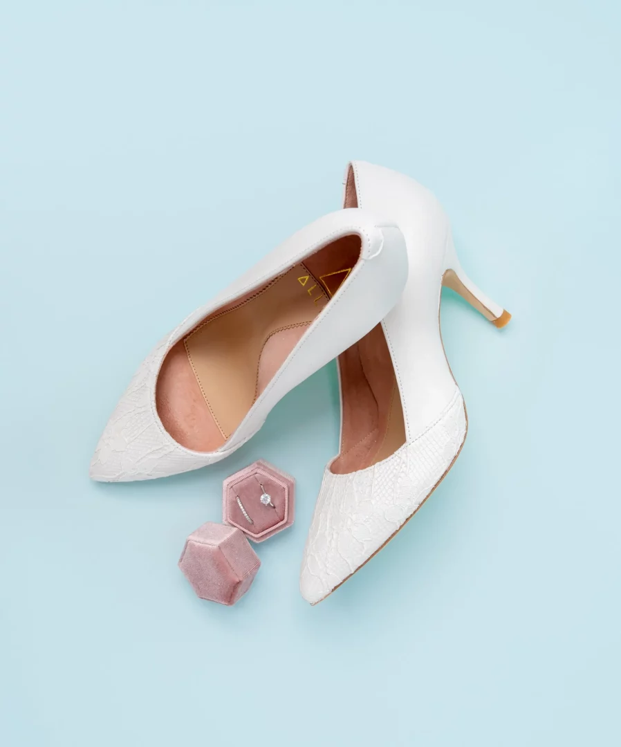 Top view photo of women's white pump shoes on light blue background