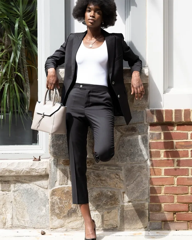 young, beautiful black model posing outside wearing black and white pant suit and with black heels